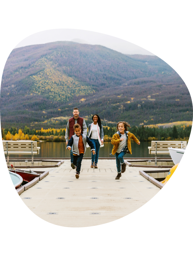 A family running down a lakeside dock.